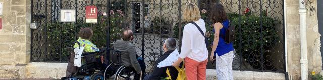 Personnes en fauteuil roulant devant un hôtel à Nancy