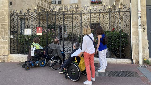 Personnes en fauteuil roulant devant un hôtel à Nancy