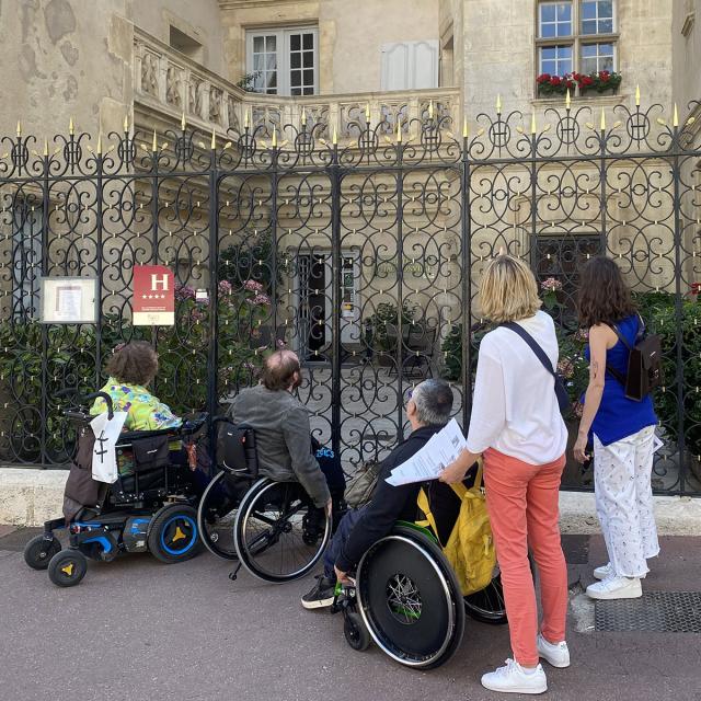 Personnes en fauteuil roulant devant un hôtel à Nancy